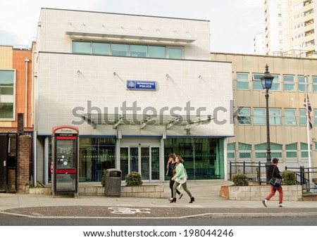 LONDON, ENGLAND - MARCH 15, 2014: Pedestrians walking past the front of Acton Police station in West London, part of the Metropolitan Police Service.