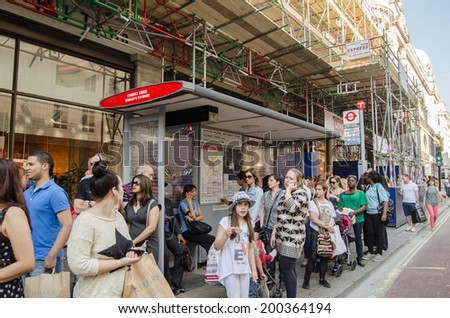 LONDON, ENGLAND - JUNE 21, 2014: Travellers waiting at a bus stop made of toy Lego bricks.  The sculpture was created from the toy bricks outside Hamley\'s toy shop to mark 200 years of London buses.