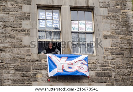 EDINBURGH, SCOTLAND - SEPTEMBER 11, 2014: An elderly man smiling from the window of his Edinburgh flat which is covered in Yes posters supporting Scottish independence in next week\'s referendum.