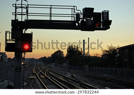 A red stop signal next to railway lines heading West at sunset.  Basingstoke railway station, Hampshire, UK.