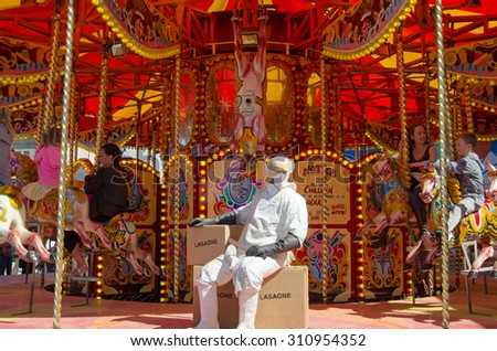 WESTON-SUPER-MARE, UK - AUGUST 26, 2015:  An abattoir worker resting on a box of carousel horsemeat lasagne, Dismaland.  The Banksy inspired parody of a theme park has attracted thousands of visitors.
