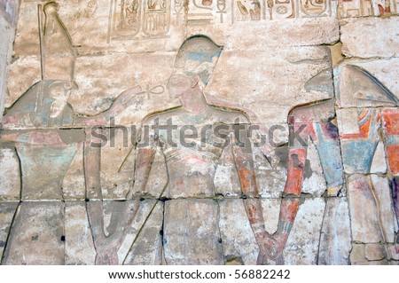 Horus, Ramses and Khnum Falcon headed god Horus and goat headed creator god Khnum with Ramses II between them.  Temple to Osiris at Abydos, Egypt.