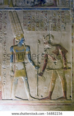 Amun god and Pharaoh Seti Carving on an interior wall at the ancient temple to Osiris at Abydos, Egypt.  The god Amun is shown wearing his double crown, before him is the Pharaoh Seti.