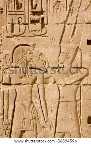 Ancient Egyptian hieroglyphic carving of the King God Amun Ra with Ramses II.  Amun is holding the ankh key of life to the Pharoah\'s face.  Temple of Medinet Habu, Luxor, Egypt.