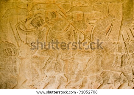 Ancient bas relief carving of cavalry soldiers waving their weapons in battle.  Southern gallery of Angkor Wat Temple, Siem Reap, Cambodia.  Carved in twelfth century.