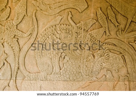 Ancient Khymer carving of the creation of the world with god fighting demons  A Chinese Lion is fighting a crocodile.  Churning of the Ocean of Milk gallery, Angkor Wat, Siem Reap, Cambodia.