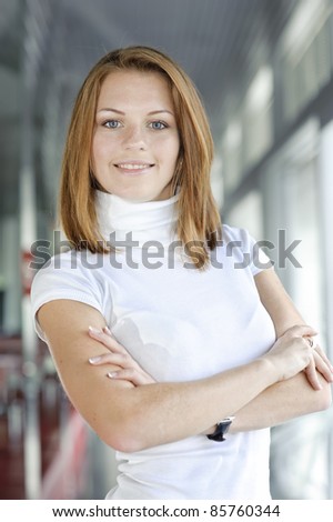 businesswoman standing in front of office windows, smiling