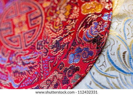 Close-up of bright red cloth over white cloth with Chinese embroidery