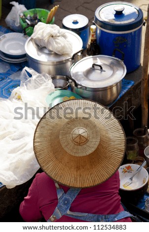 View from above of a street food stall with vendor wearing straw hat