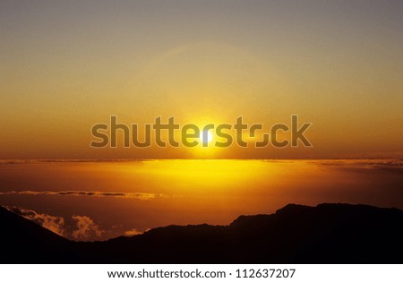 Panorama of sunset orange sky with sun shining above clouds, view from mountain peak