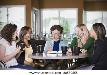 Group Of Girls Listening To Senior Woman In Restaurant