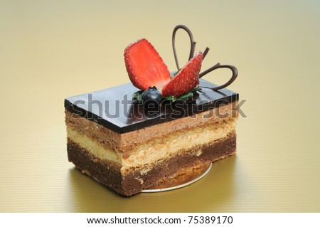 A Chocolate short cake with sliced strawberry on gold background