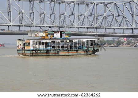 KOLKATA, INDIA - OCTOBER 27: Old ferry boat crosses the Hooghly River nearby the Howrah Bridge on October 27, 2009.  To use the ferry is easy, fast and cheap way how to cross the Hooghly River.