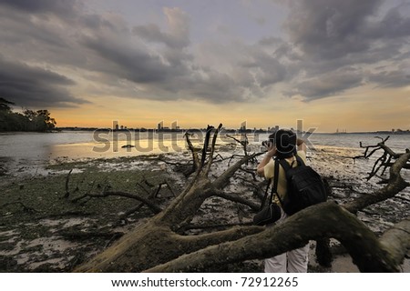 Nature photographer with camera at Singapore kranji beach against skyline