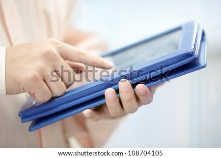 Hands of man in pink shirt using tablet PC indoors
