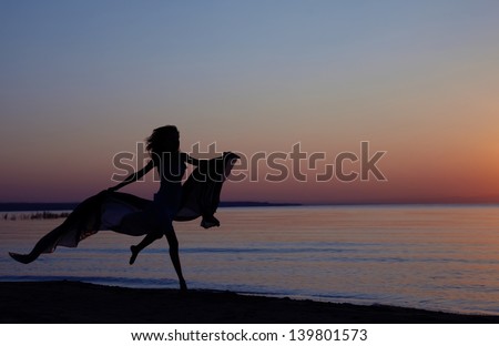 Silhouette of the woman flying at the sea during beautiful sunset. Natural light and darkness. Vibrant colors added