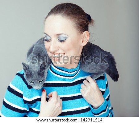 Smiling lady pampering her cat indoors. Natural light and colors
