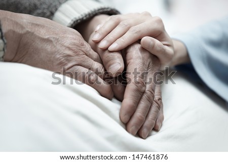 Hand of woman touching senior man in clinic
