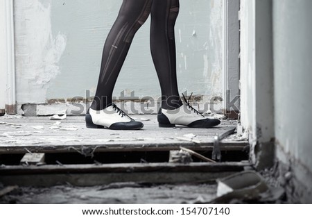 Human legs in stylish shoes standing on the old dirty wooden floor