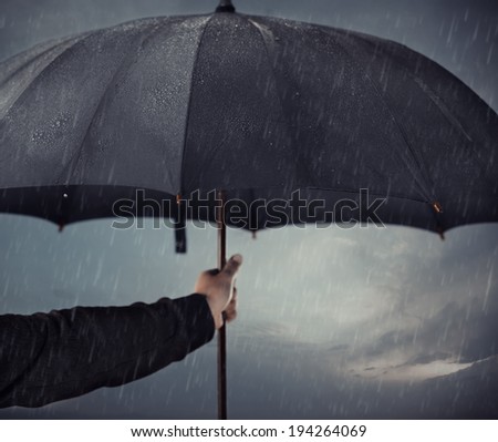 Human hands holding big black umbrella under the heavy rain