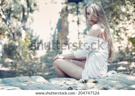 Beautiful lady in white shirt outdoors sitting on a bedding