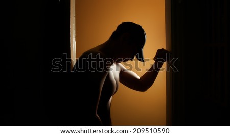 Silhouette of the muscular baseball player in the dark interior