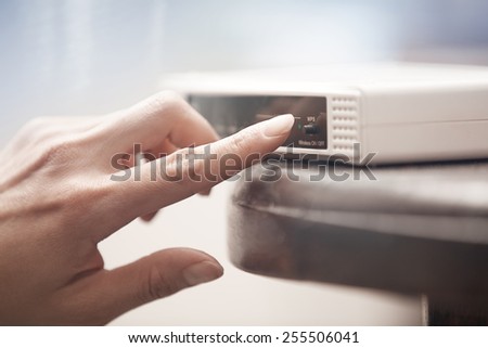 Human hand turning on wireless modem. Close-up horizontal photo
