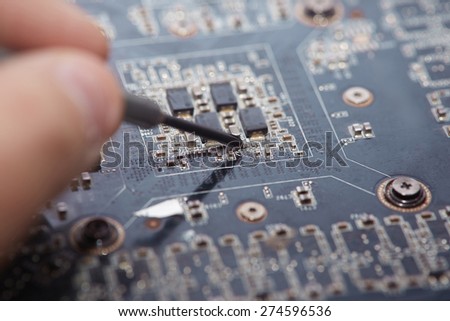 Human fingers making repair of motherboard. Close-up photo