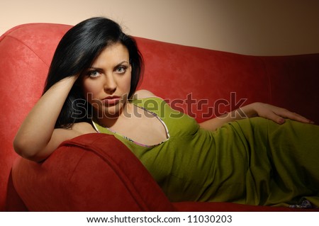 Elegant model laying on the red sofa in dark room