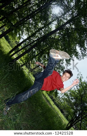 Outdoors photo of the cheerful boy doing karate kick