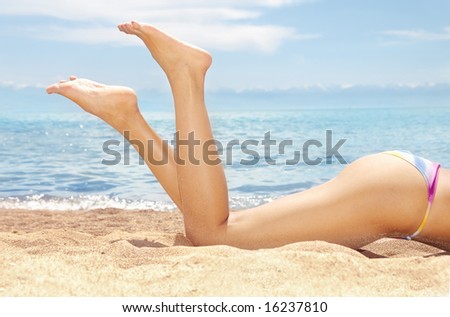 Woman body in bikini laying on a beach under the sunlight