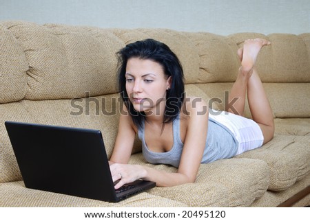 Serene lady laying on sofa and working a laptop