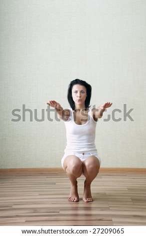 Sportive lady doing squatting at home