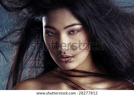 Portrait of the sexy Asian witch with blowing hairs and bronze skin