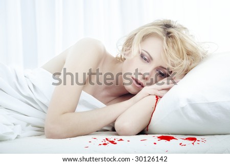 Bleeding beautiful sad woman laying on the bed