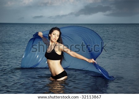 Lady with perfect body dancing in the sea with blue fabric