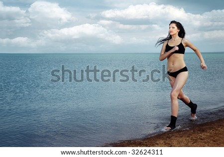 Healthy lady in black sportive costume running along the sea