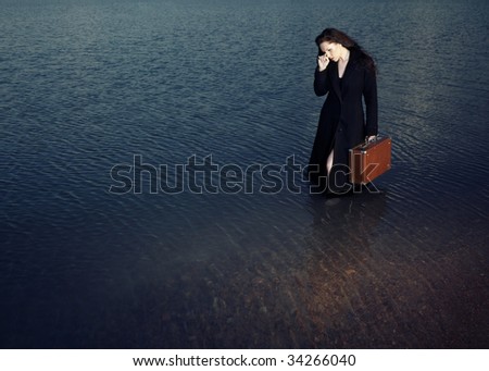 Sad alone woman with bag standing in the water