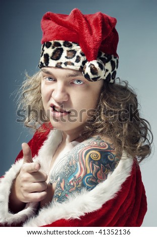 stock photo Bad man with colored tattoo in the red Santa Claus costume