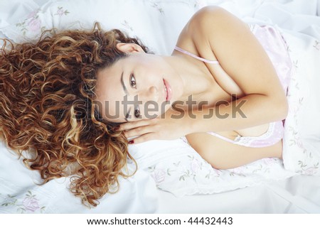 Pretty lady with curly hairs laying on a bed