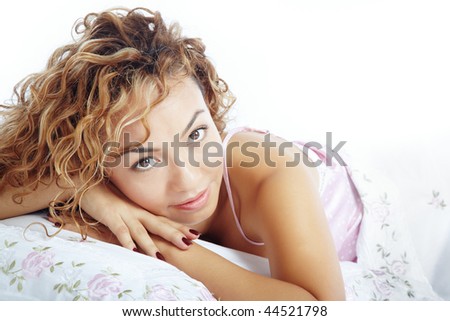 Pretty lady with curly hairs laying on a bed