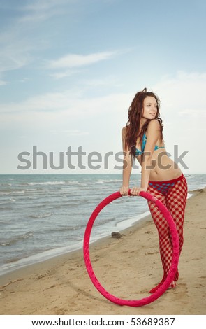 Elegant lady outdoors standing near the red sportive Hula hoop at the beach