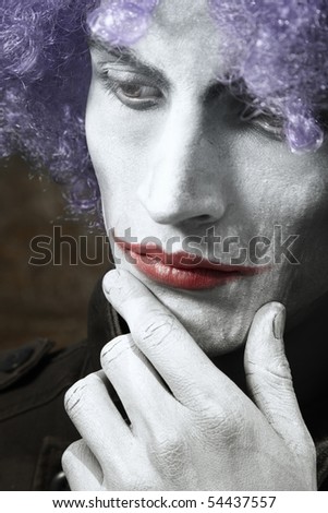 Single sad funny man with theatrical makeup and wig. Vertical photo with dramatic colors and toning
