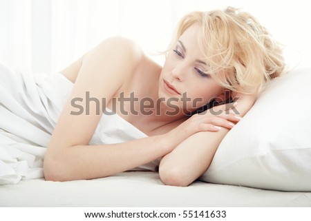 Sad lady indoors laying in the white bedroom at the early morning