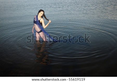Sensual lady in bikini standing in the water. Horizontal photo