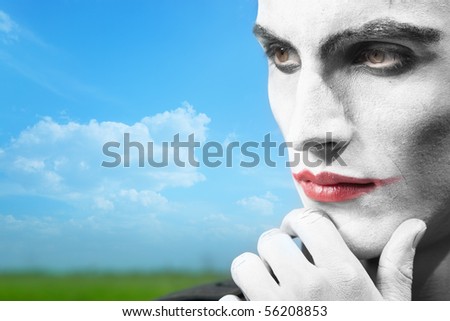 Pensive clown outdoors with theatrical makeup. Horizontal photo, artistic vibrant colors added
