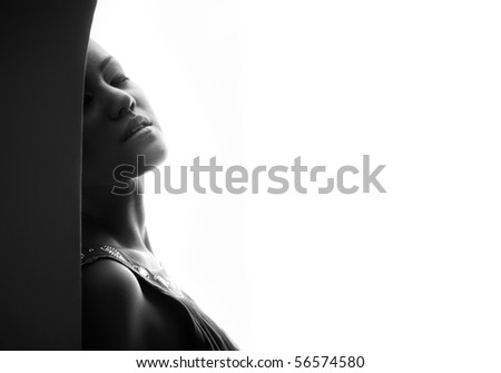 Passionate lady indoors on a white background. Black and white photo with artistic darkness and shadows