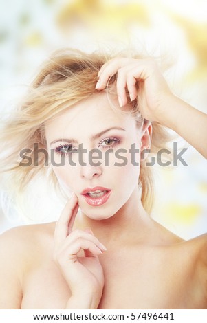 Sexy blond lady outdoors with blown hairs. Defocused nature details on background. Natural colors