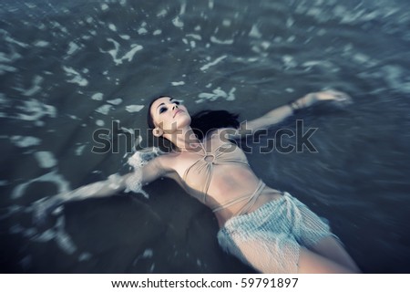 Beautiful lady relaxing and laying in the water. Artistic shallow depth of field added for natural view