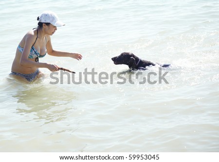 Happy lady on vacation swimming and playing with her dog. Artistic colors added